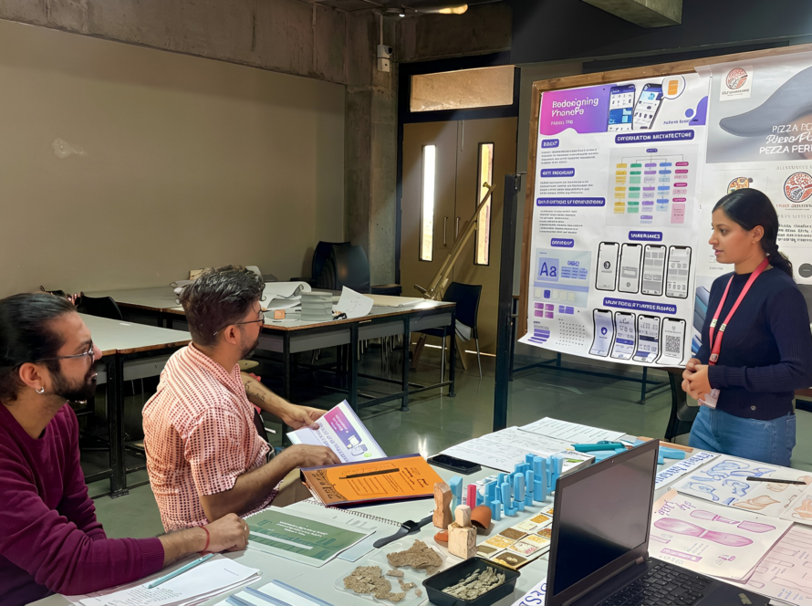 Two Men sitting on a table taking a design Jury of a girl student in a classroom