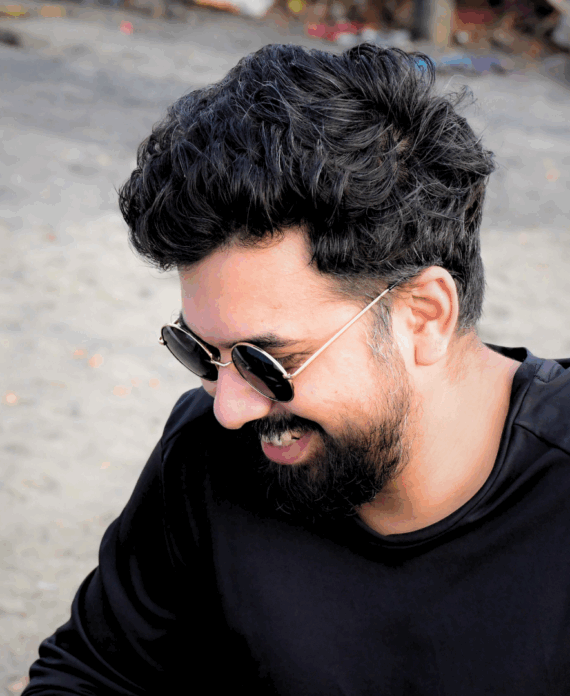 A side profile of a Smiling Indian Man with a beard and sunglasses.